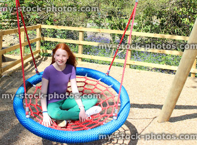 Stock image of young child playing in woodland playground, on cradle swing