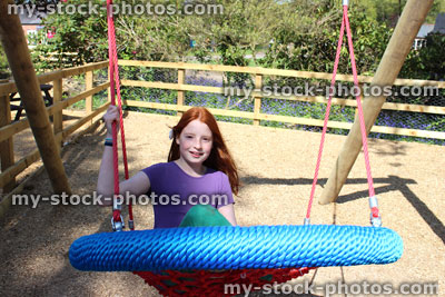 Stock image of young child playing in woodland playground, swinging forwards