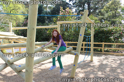 Stock image of young child playing in woodland playground, on wooden climbing frame