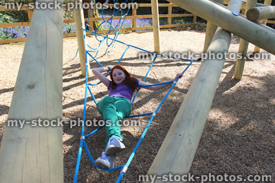 Stock image of young child playing in woodland playground, wooden climbing frame