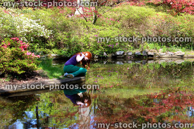 Stock image of girl sitting by pond in Japanese garden, with koi carp