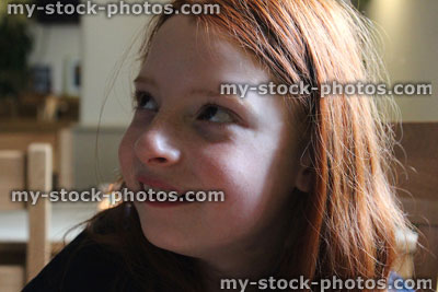 Stock image of young girl with long red hair, thinking, day dreaming