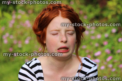 Stock image of girl in flower gardens with hayfever, sneezing, runny nose, allergies