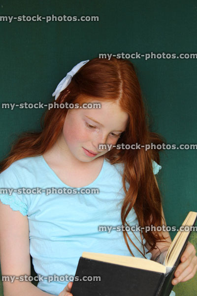 Stock image of young girl reading school book, garden swing seat