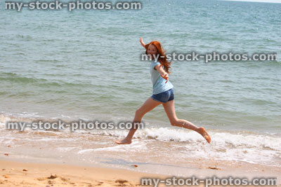 Stock image of girl running barefoot on beach / sea / seaside exercise jumping, jogging