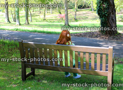 Stock image of girl with red hair sat on garden bench