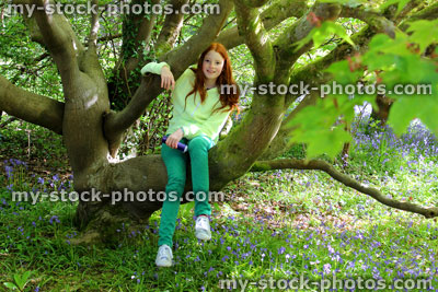 Stock image of pretty girl climbing on trunk and branches of rhododendron tree