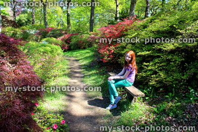 Stock image of young girl sitting on garden bench by pathway
