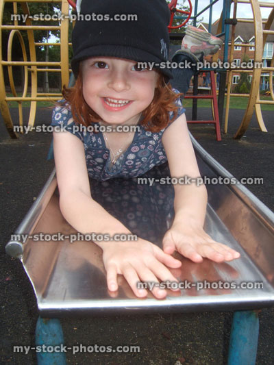 Stock image of young read headed girl playing on a slide