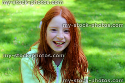 Stock image of girl with long red hair laughing on lawn