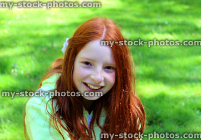 Stock image of girl with long red hair smiling on lawn
