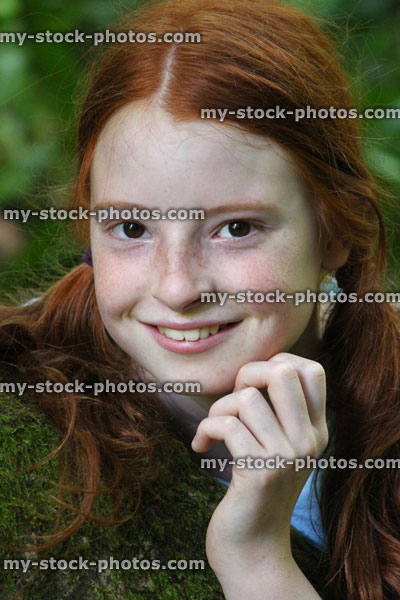 Stock image of pretty young girl smiling in sunshine, long red hair, pigtails