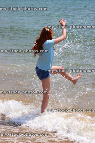 Stock image of girl on beach, playing, splashing, padding in sea