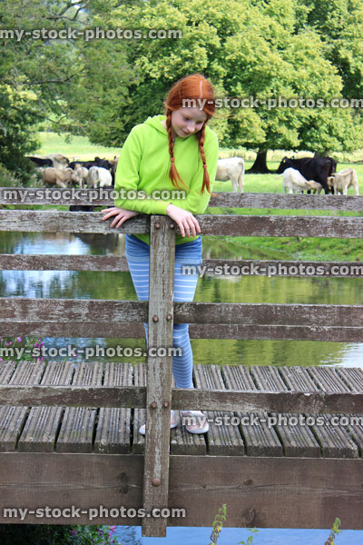 Stock image of girl standing on wooden bridge, countryside, looking down at river