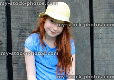 Stock image of girl sitting on garden bench with long hair, hat, dress