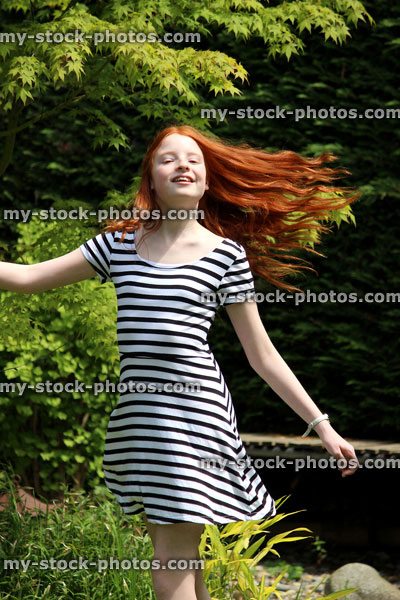 Stock image of girl with long hair and dress spinning around in garden