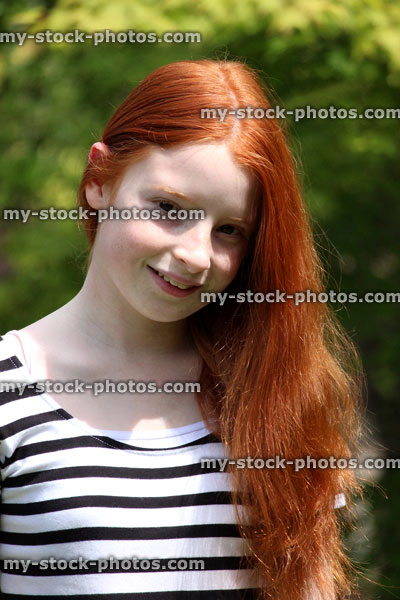 Stock image of girl with long red hair on one side, in sunshine