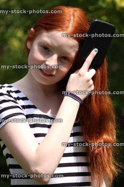 Stock image of pretty girl brushing her long red hair outside in sunshine