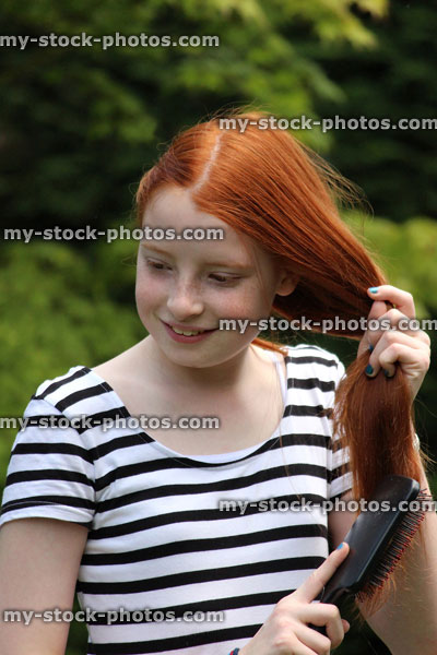 Stock image of girl brushing her long red hair outside in sunshine