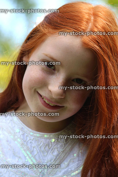 Stock image of beautiful, happy girl with long red hair, outside in the garden
