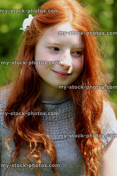 Stock image of pretty, happy girl with long red hair in the garden