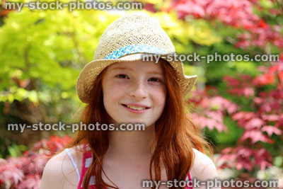 Stock image of attractive young happy girl in the garden sunshine wearing straw hat
