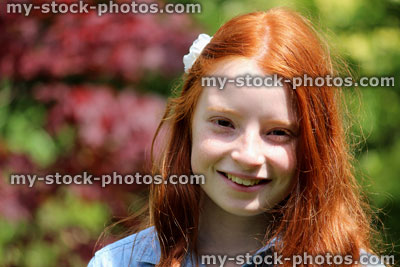 Stock image of pretty, happy girl with long red hair, outside in the garden