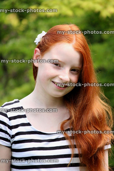 Stock image of girl with long red hair brushed to side, in sunshine