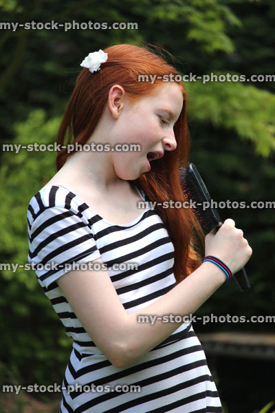 Stock image of girl singing into her hairbrush, pretending to be pop star