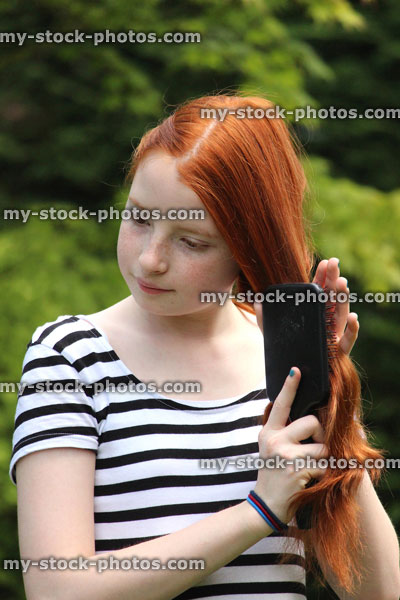 Stock image of model girl brushing her long red hair outside in sunshine