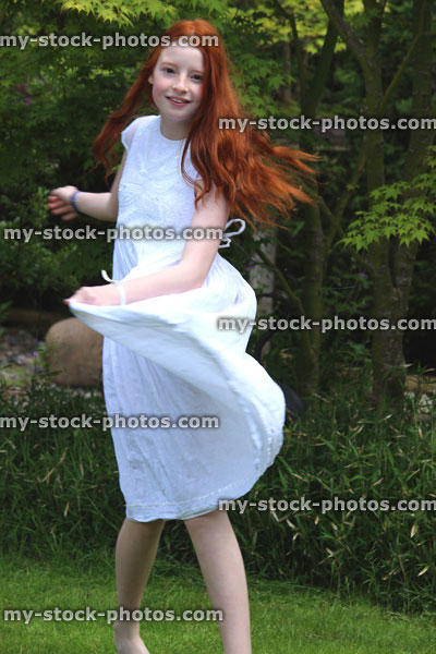Stock image of girl with long hair and dress spinning around in garden