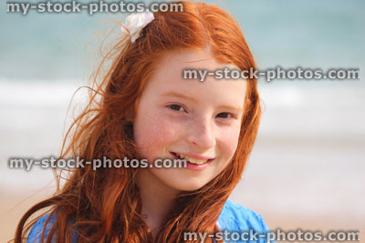 Stock image of girl standing on beach by sea, seaside summer holiday, flower in hair