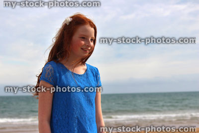 Stock image of girl standing on beach by sea, seaside summer holiday, blue dress