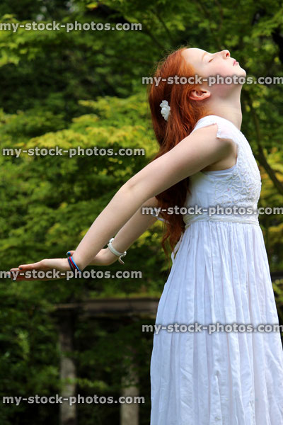 Stock image of pretty young girl enjoying the sun in garden, white dress