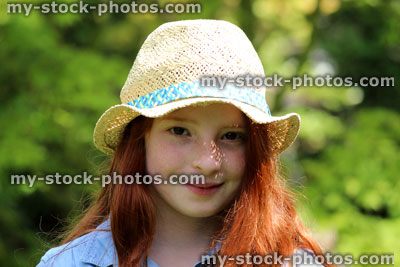 Stock image of beautiful young happy girl in garden sunshine wearing straw hat