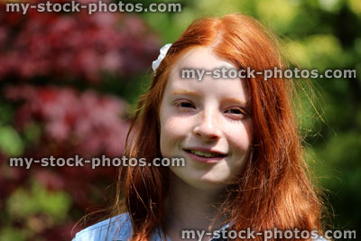 Stock image of pretty, happy girl with long red hair, smiling to herself
