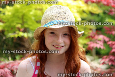 Stock image of beautiful young happy girl in the garden sunshine wearing straw hat