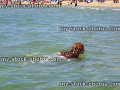 Stock image of girl swimming close to sandy beach / seashore / seaside holiday