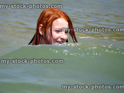 Stock image of girl swimming and laughing in sea, splashed by wave