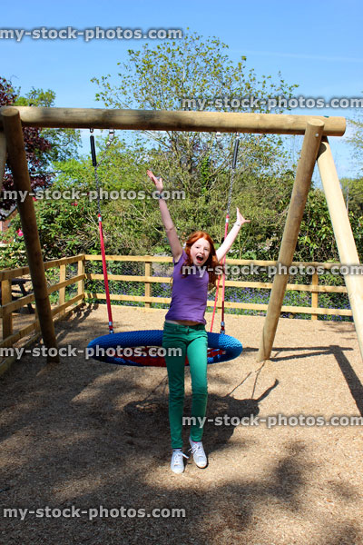 Stock image of young child playing in woodland playground, jumping off swing cradle