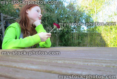 Stock image of girl looking along wooden table in garden, perspective photo 