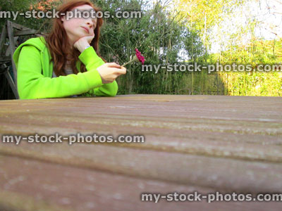 Stock image of girl looking along wooden table in garden, perspective photo