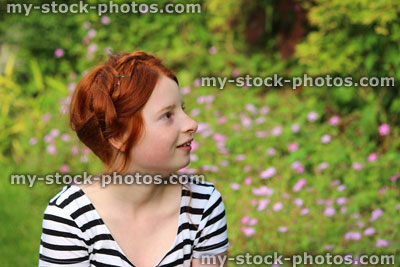 Stock image of young girl daydreaming in summer garden, looking up / looking upwards