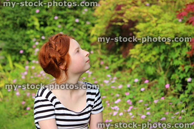 Stock image of young girl daydreaming in summer garden, looking up / looking upwards
