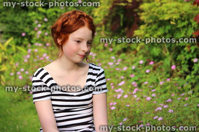 Stock image of young girl daydreaming in summer garden, looking down / looking downwards