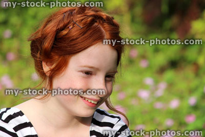 Stock image of girl in garden, smiling with milkmaid braid hairstyle