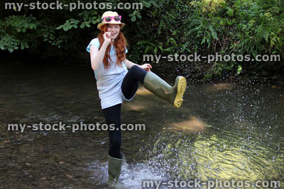 Stock image of girl playing, paddling, splashing, wading in river, woodland