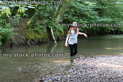 Stock image of girl playing, paddling, splashing, wading in river, woodland