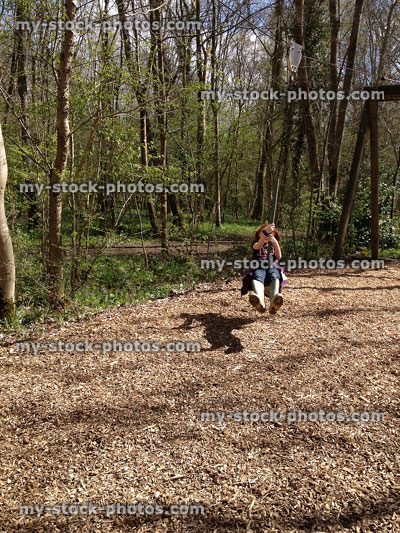 Stock image of young girl sliding down zip line / wire in woodland playground