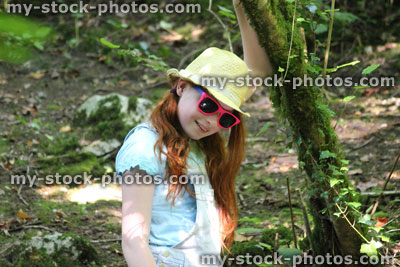 Stock image of girl in woodland, forest, straw hat, pink sunglasses